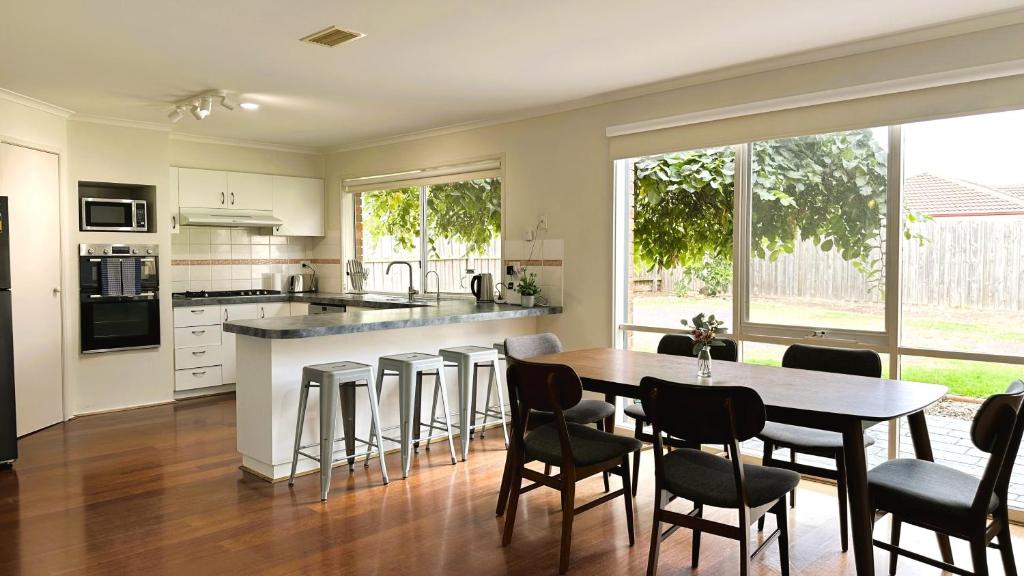 a kitchen with a table and chairs and a kitchen with a counter at Near Airport and Easy to Melbourne CBD by GoodLive in Sydenham