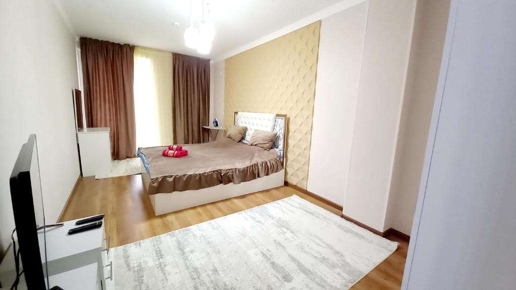 ein kleines Schlafzimmer mit einem Bett und einem Fernseher in der Unterkunft 2х комнатная квартира в ЖК Отау сити in Schymkent