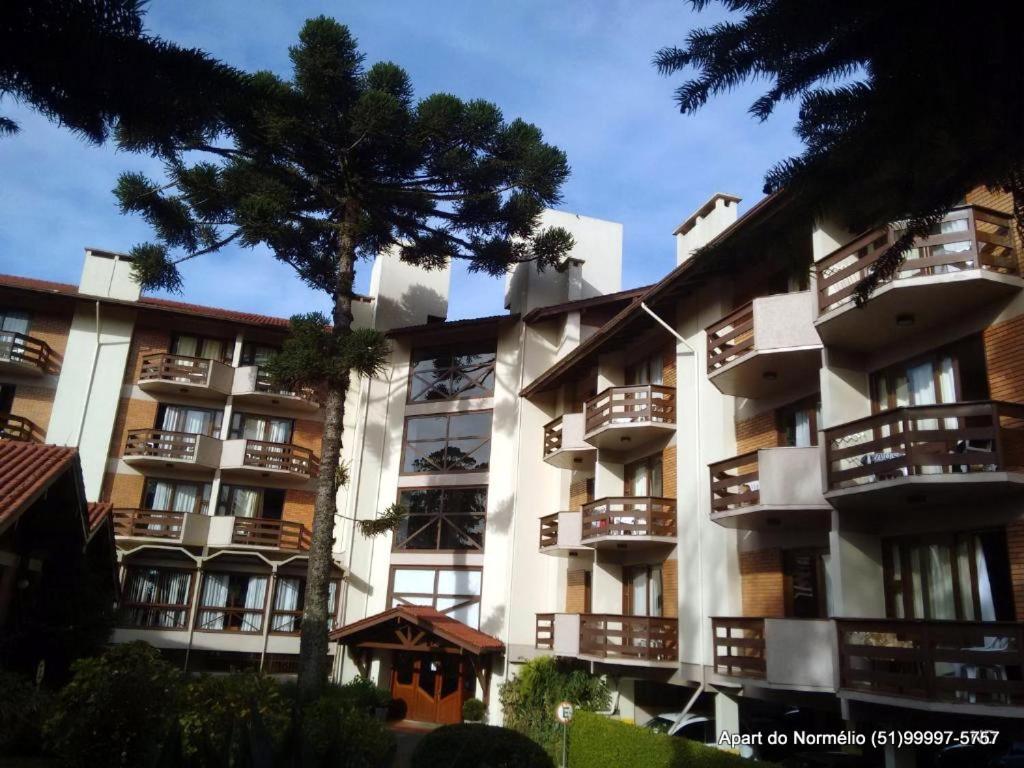 um grande edifício de apartamentos com uma árvore em frente em Gramado Serrano em Gramado