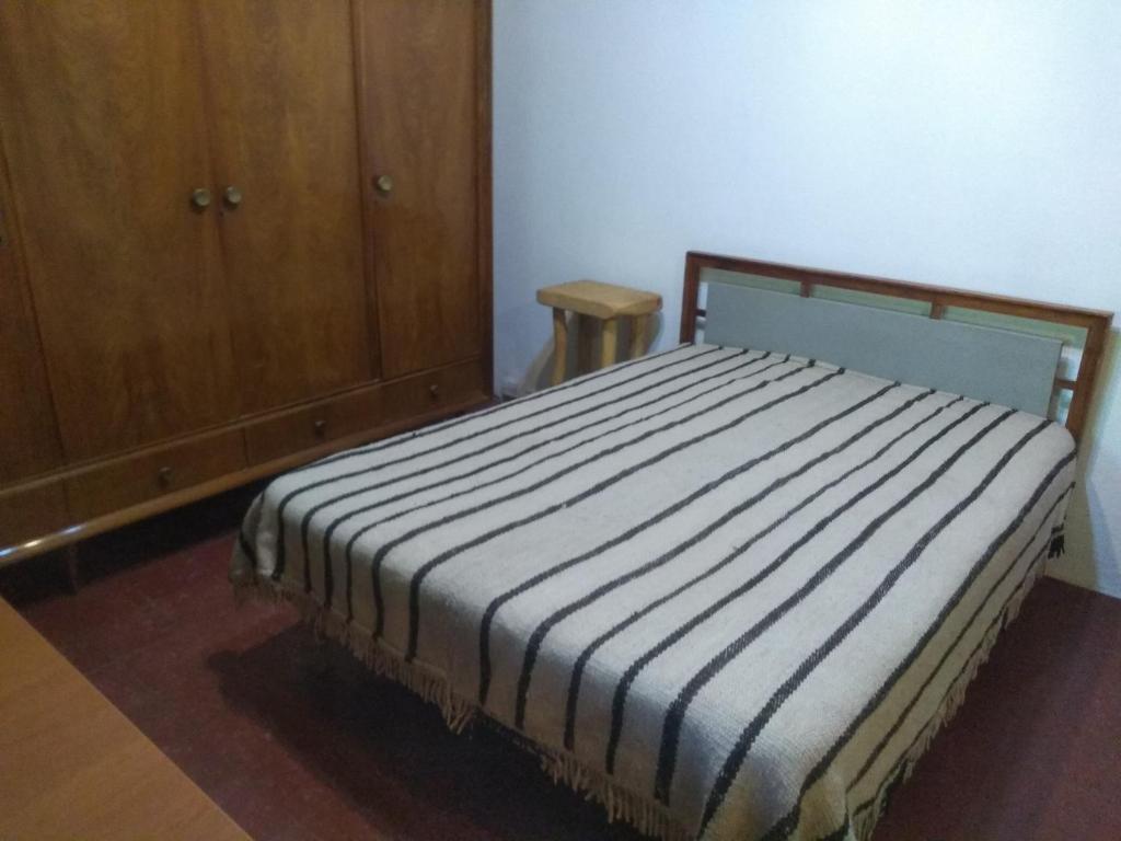 ein Bett in einem Zimmer mit einem Holzschrank in der Unterkunft Casa Alma Verde calma in Luyaba