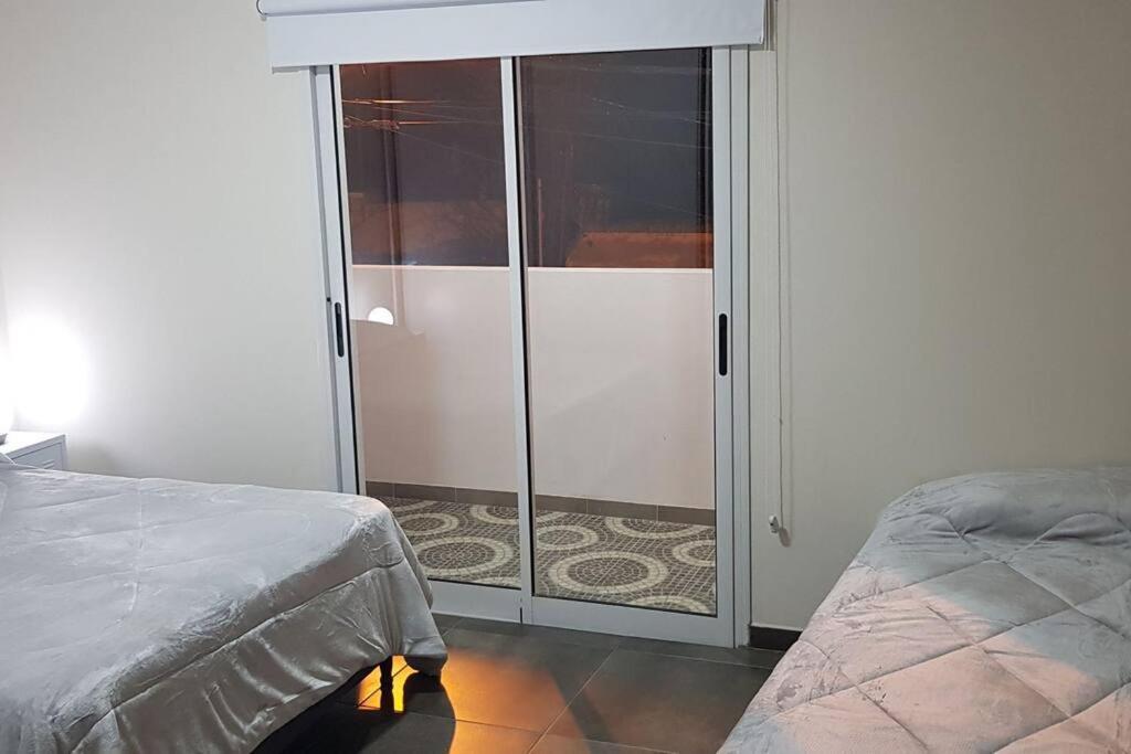 1 dormitorio con una puerta corredera de cristal y 1 cama en Dpto Falucho en San Luis