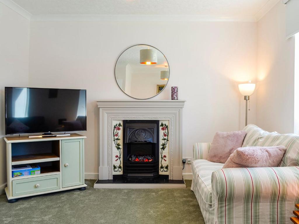 a living room with a fireplace and a mirror at India Lane Cottage in Montrose