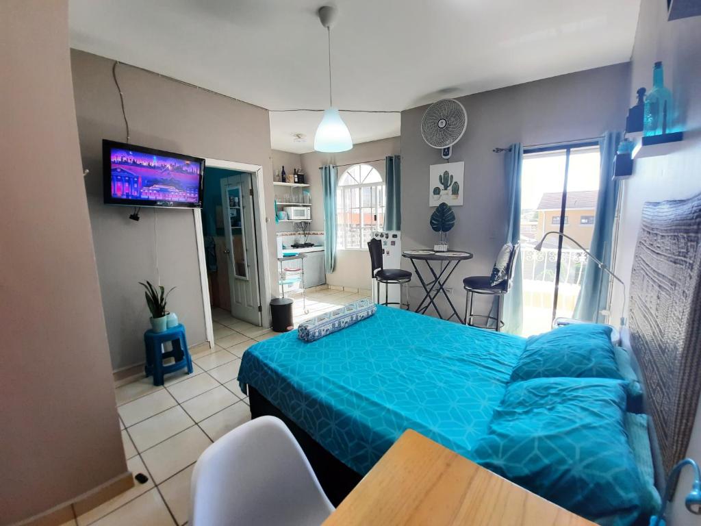 a bedroom with a blue bed and a table and chairs at Encantador Apartamento Equipado in Tegucigalpa