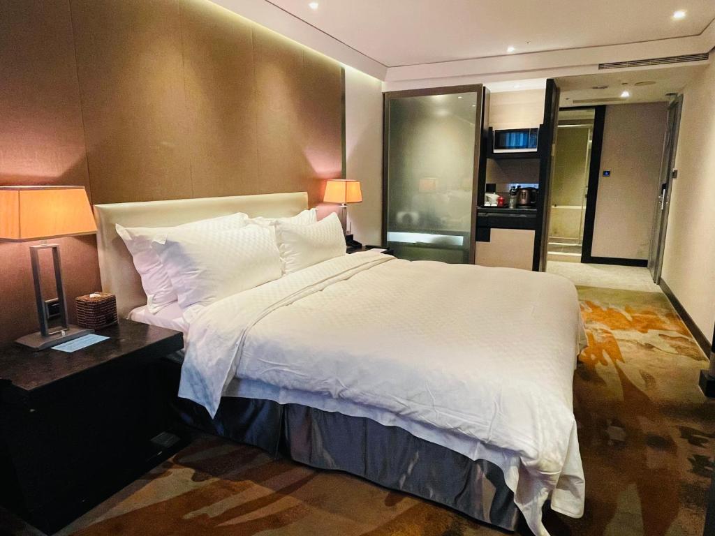 a bedroom with a large white bed and two lamps at The Tango Taichung in Taichung