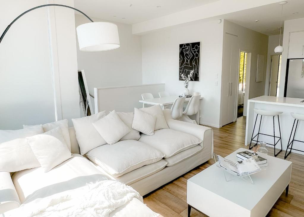 a living room with a white couch and a table at Luxury 2 Bedroom Apartment with cocktail bar and espresso machine in Auckland