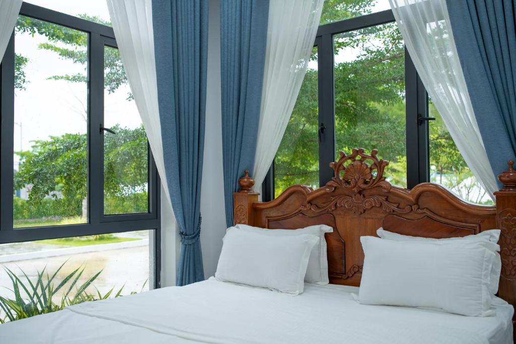 łóżko z białą pościelą i poduszkami w pokoju z oknami w obiekcie Damnak Borey Resort w mieście Kâmpôt