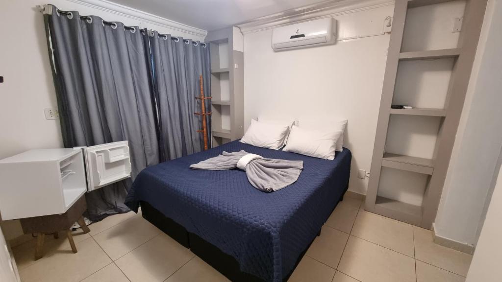 a bedroom with a bed with a blue comforter at Zênit Hostel da Cris in Cabo Frio