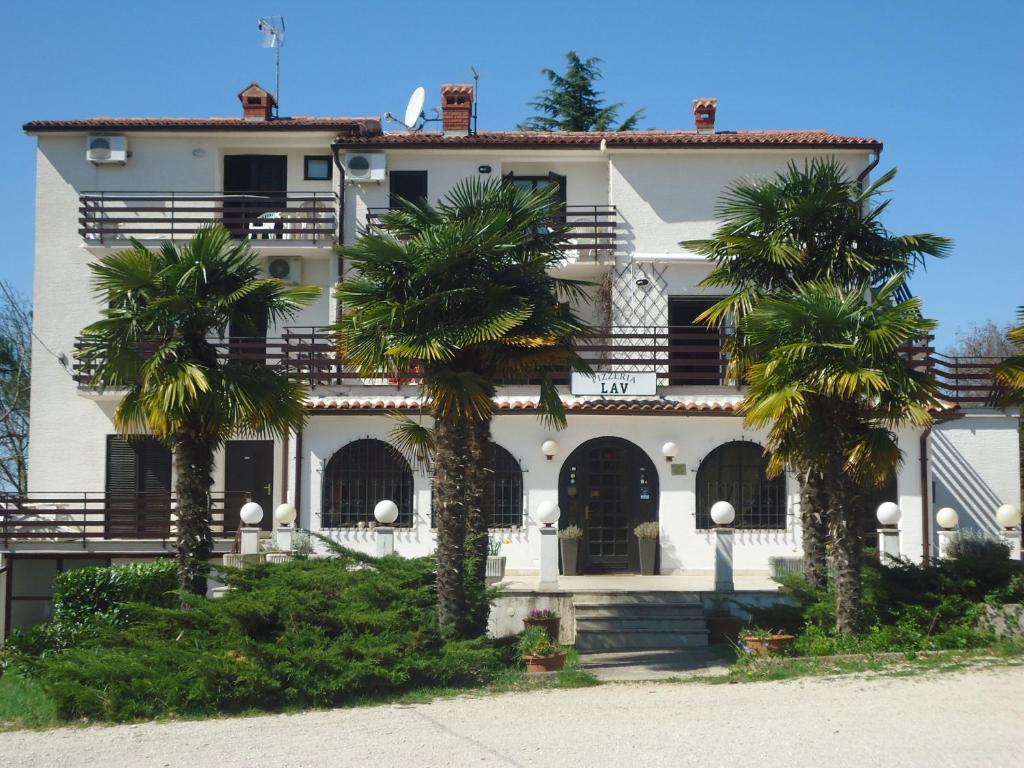 a white building with palm trees in front of it at Apartments Lav in Umag