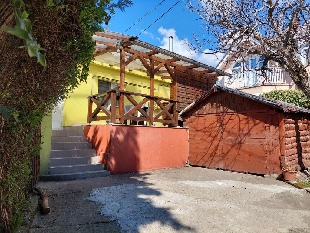 a yellow house with a wooden gate and a garage at Dizike Pet-friendly Guesthouse in Budapest