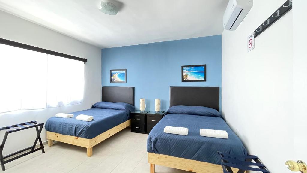 a bedroom with two beds and a blue wall at Habitacion Privada Ejecutiva Confortable Minisplit Amenidades 1 in Castillo Teresa