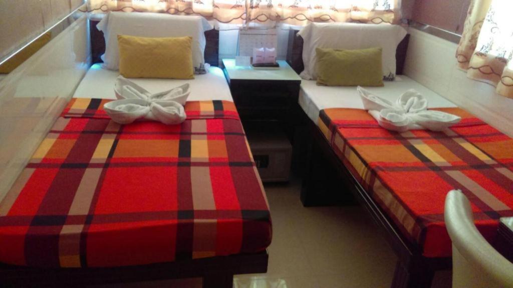 two twin beds in a room with a red and stripes at London Guest House in Hong Kong