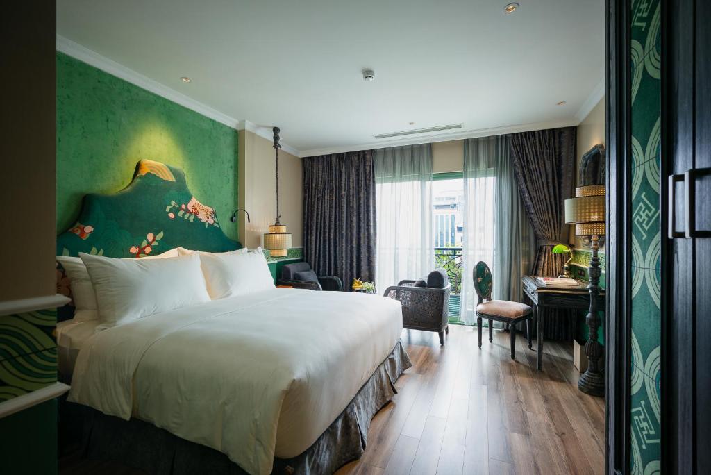 a hotel room with a large bed and a desk at Smarana Hanoi Heritage - Hotel and Retreats in Hanoi