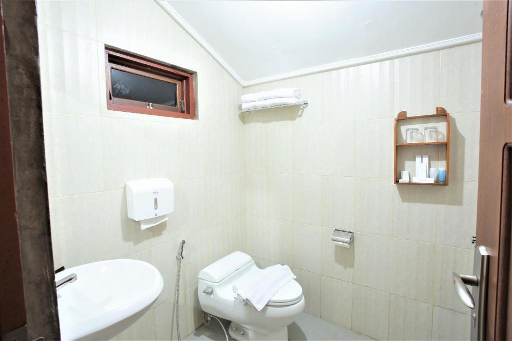 a white bathroom with a toilet and a sink at Kasuari Exotic Resort Magelang in Magelang