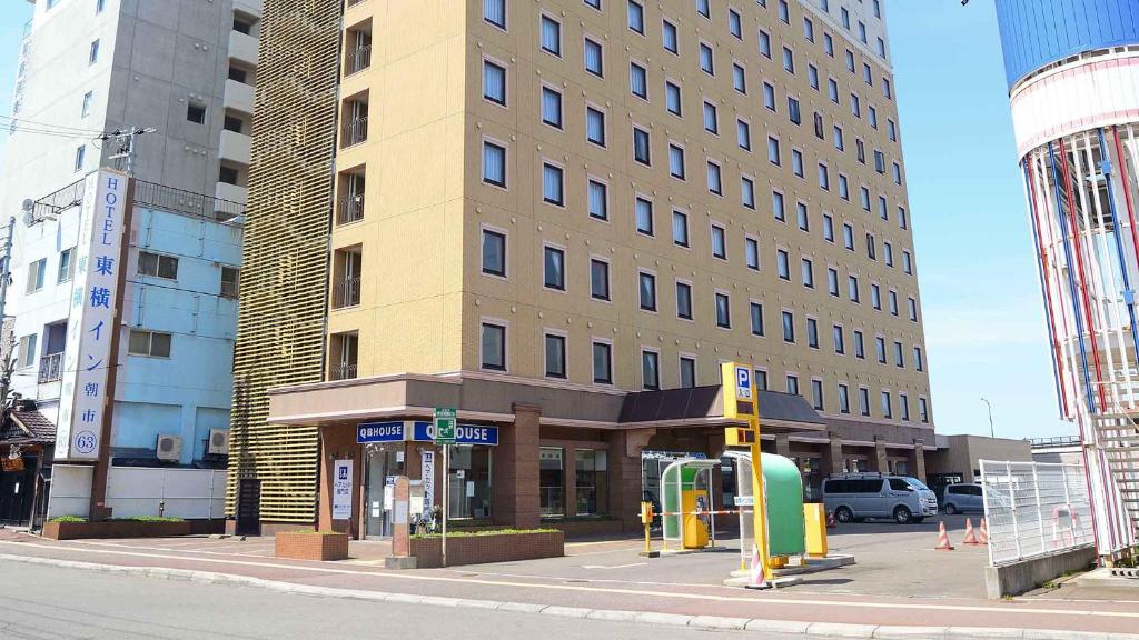 ein hohes Gebäude in einer Stadtstraße mit einer Bushaltestelle in der Unterkunft Toyoko Inn Hokkaido Hakodate Ekimae Asaichi in Hakodate