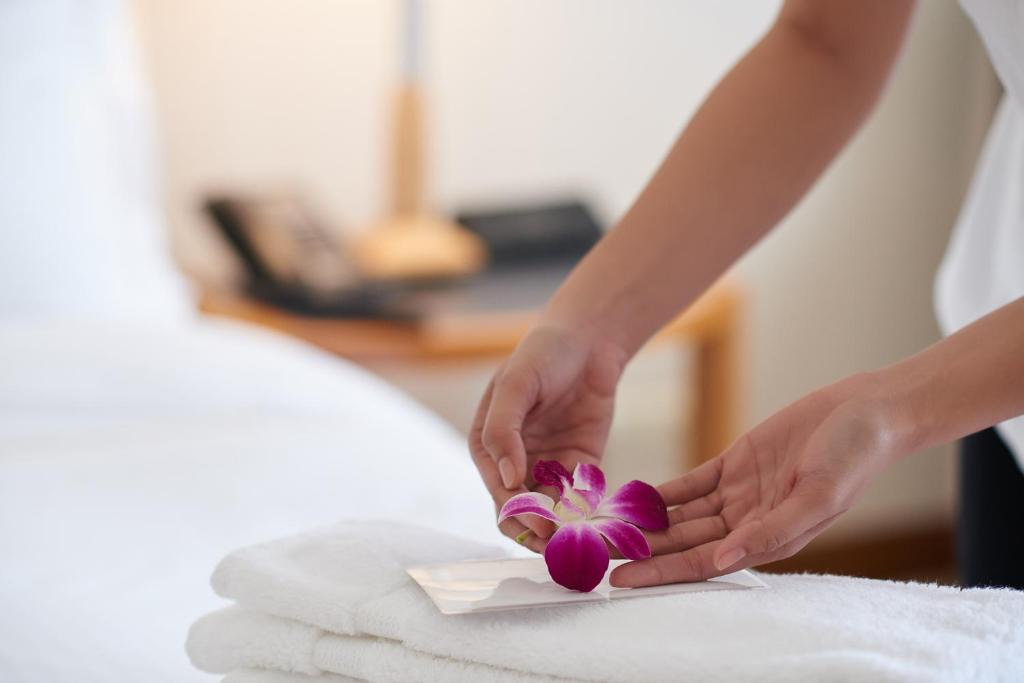 那覇市にあるmaejima Hotelの紫の花をベッドに抱く女