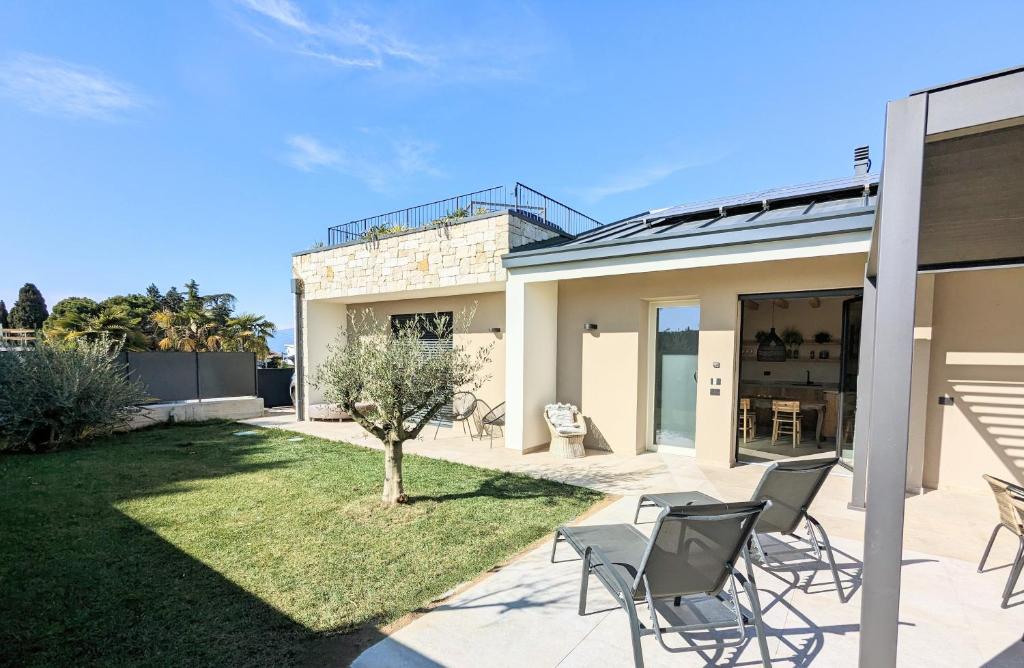 a home with a patio and lawn with chairs at Villa Agapanto in Pacengo di Lazise