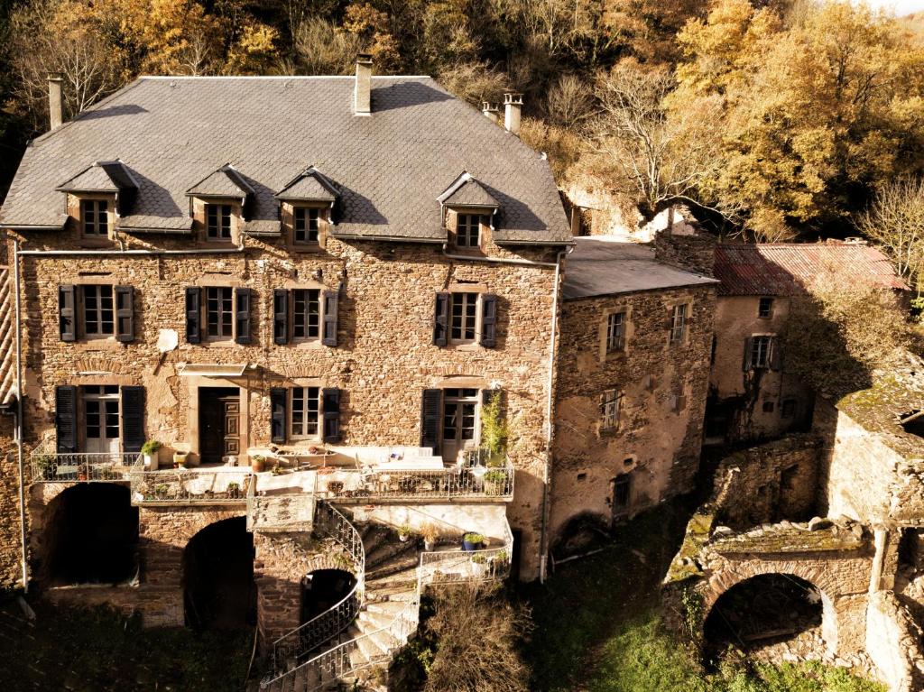 uma antiga casa de pedra com um telhado numa ponte em Rêve Aveyron em Broquiès