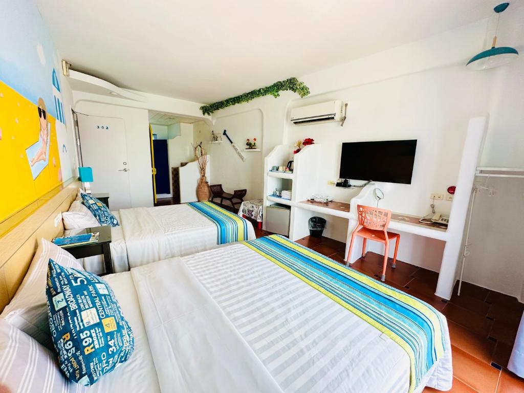 a bedroom with two beds and a desk with a tv at 海灘戀情 Beach Love 近沙灘-國旅卡特約商店 in Eluan