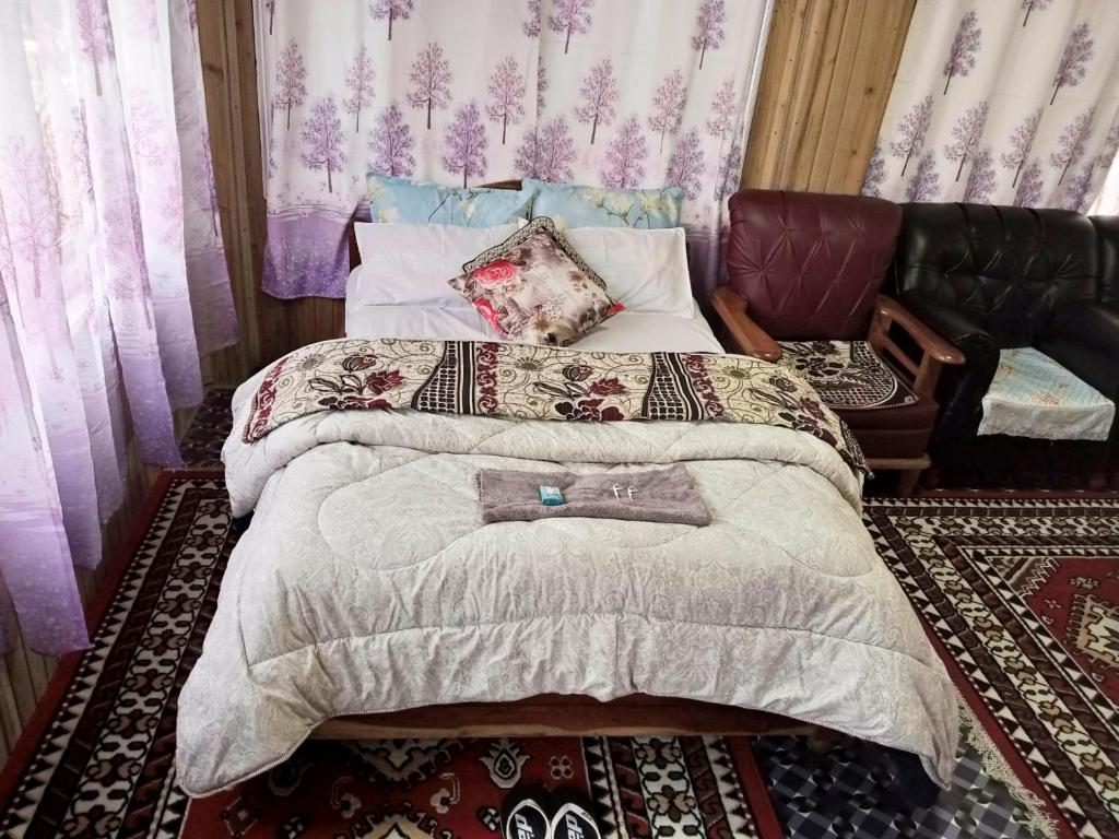 um quarto com uma cama grande e uma cadeira em SILENT AM HOMESTAY em Darjeeling