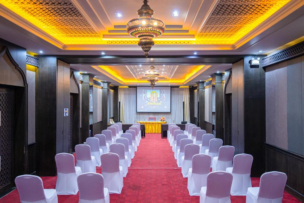 a row of white chairs in a room with a stage at Amman Unique Hotel in Udon Thani