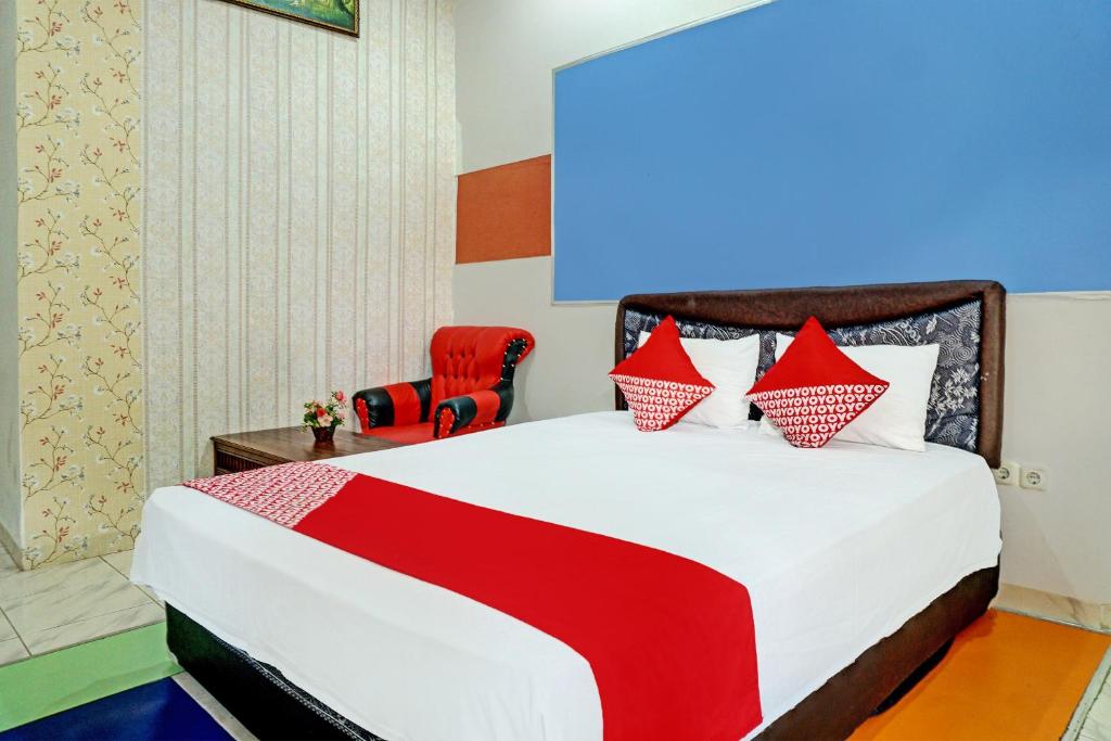 a bedroom with a bed and a red chair at OYO 92405 Evergreen Hotel & Resto 