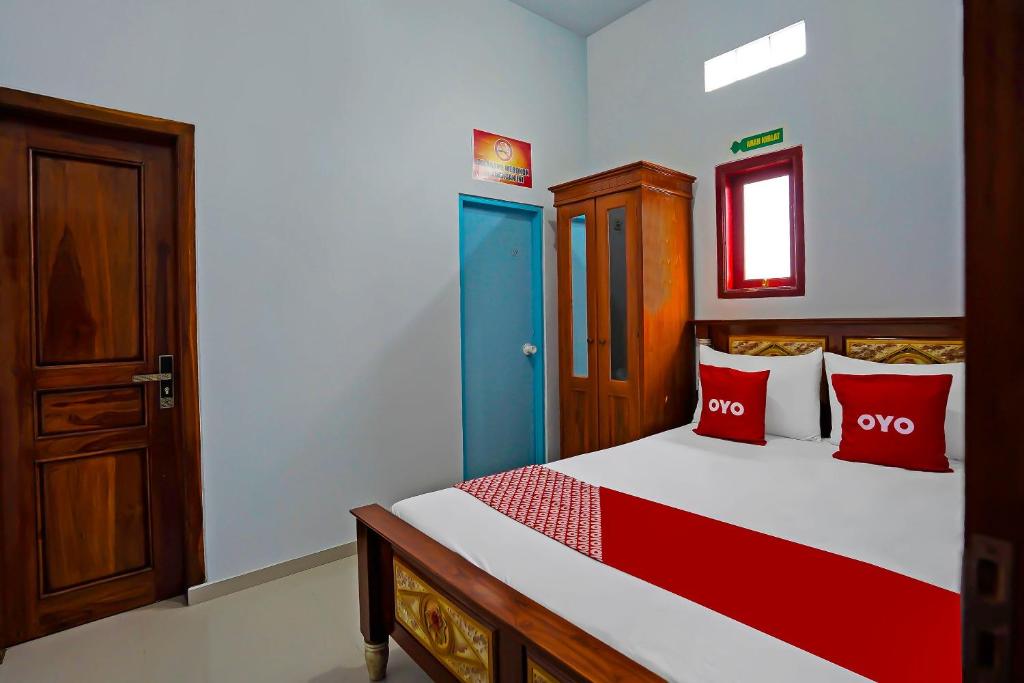 a bedroom with a bed with red and blue pillows at OYO 92416 Salsabila Homestay in Pasuruan