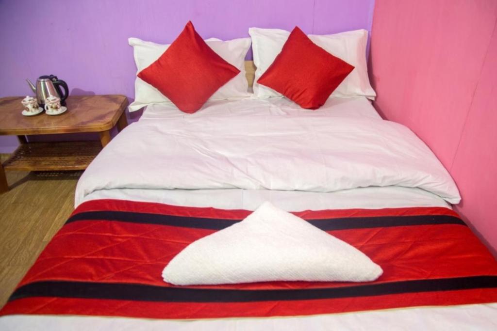 a bed with red and white pillows on it at Hill Home Stay, Baichung in Nātang