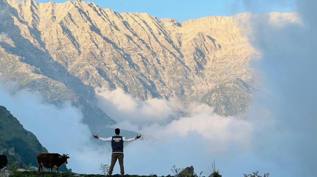 a man standing in front of a mountain at Triund Trek and Camping in Dharamshala