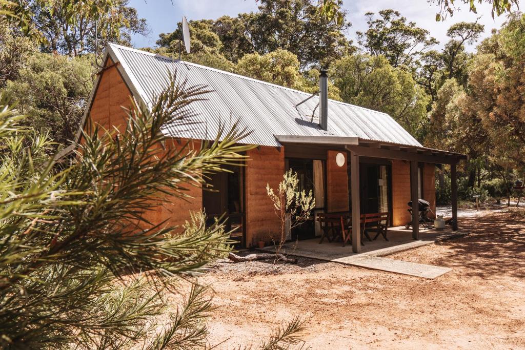 a small brick house with a metal roof at Bussells Bushland Cottages in Margaret River Town