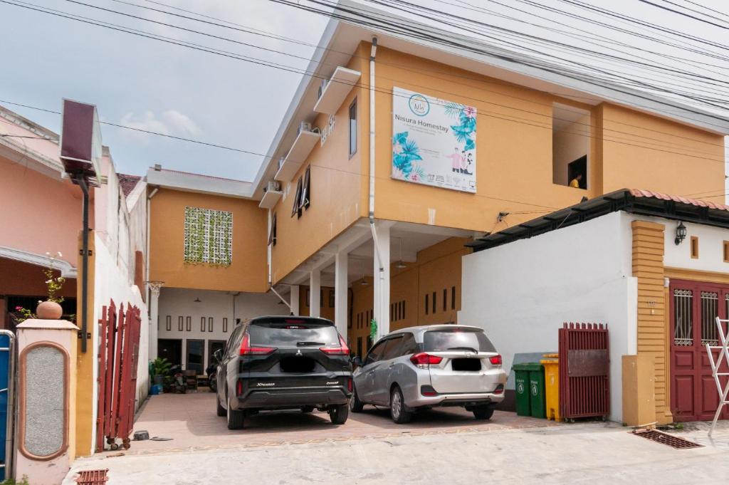 two cars parked in front of a building at Urbanview Hotel Nisura Homestay Medan by RedDoorz in Sunggal