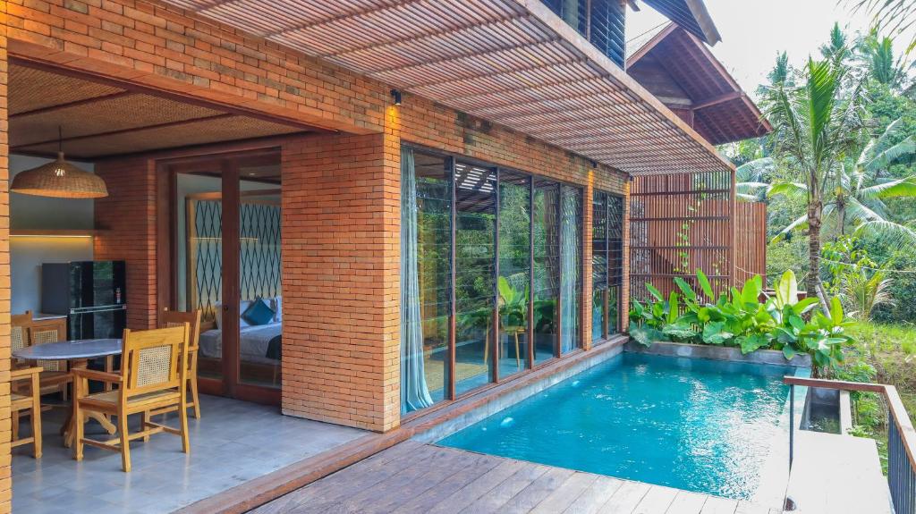 eine Terrasse mit Pool und ein Haus in der Unterkunft Hideaway Village Bali Ubud by Kanaan Hospitality in Ubud