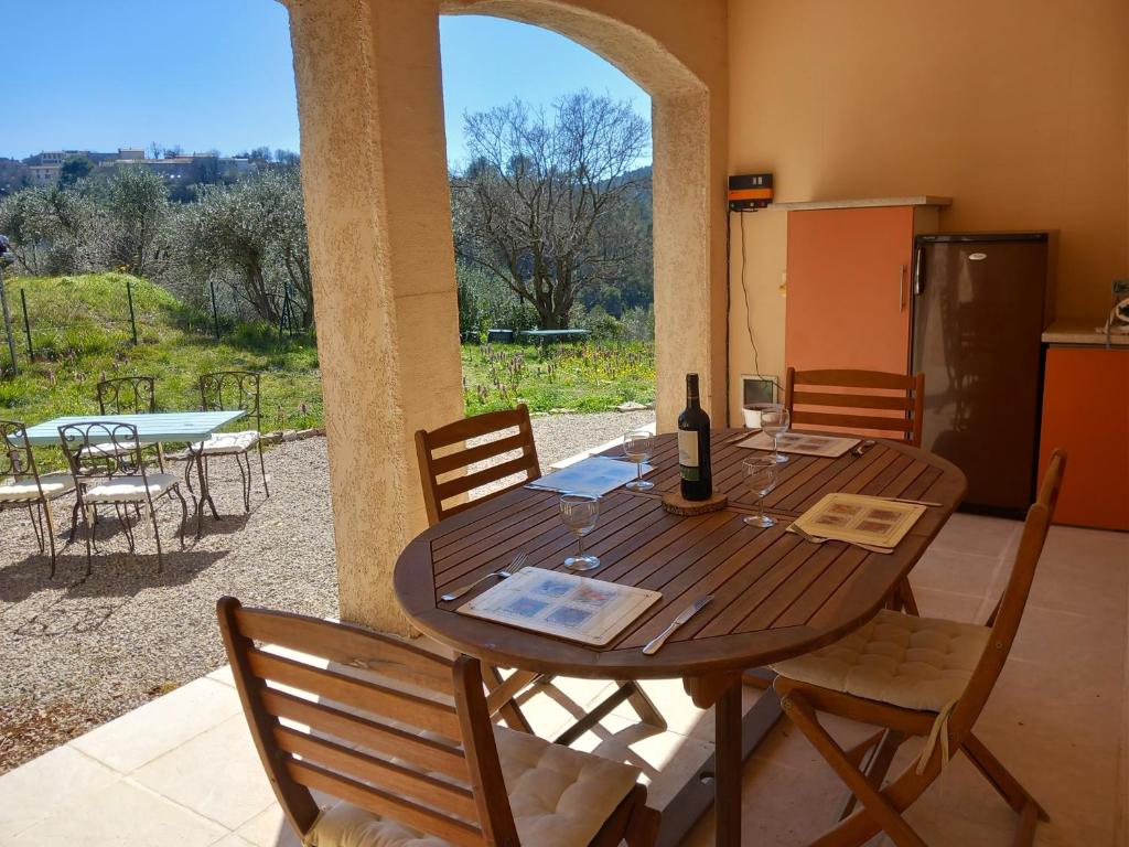 een houten tafel met stoelen en een fles wijn bij Detached villa with New pool!! Partial air-conditioning, set in a secure private garden, 800 metres from medieval village in Claviers