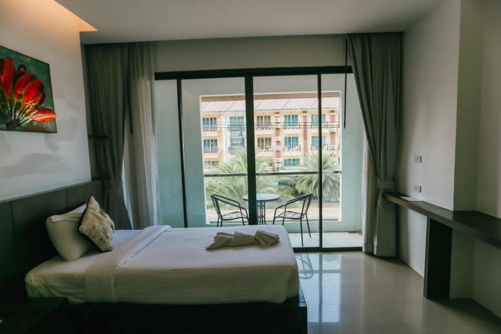 a hotel room with a bed and a large window at Phranang Place- SHA Extra in Ao Nang Beach