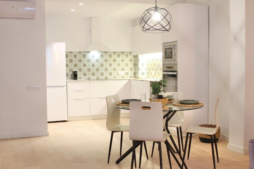 een witte keuken met een tafel en stoelen bij Mediterranean Way - Cavaller Suites in Tarragona