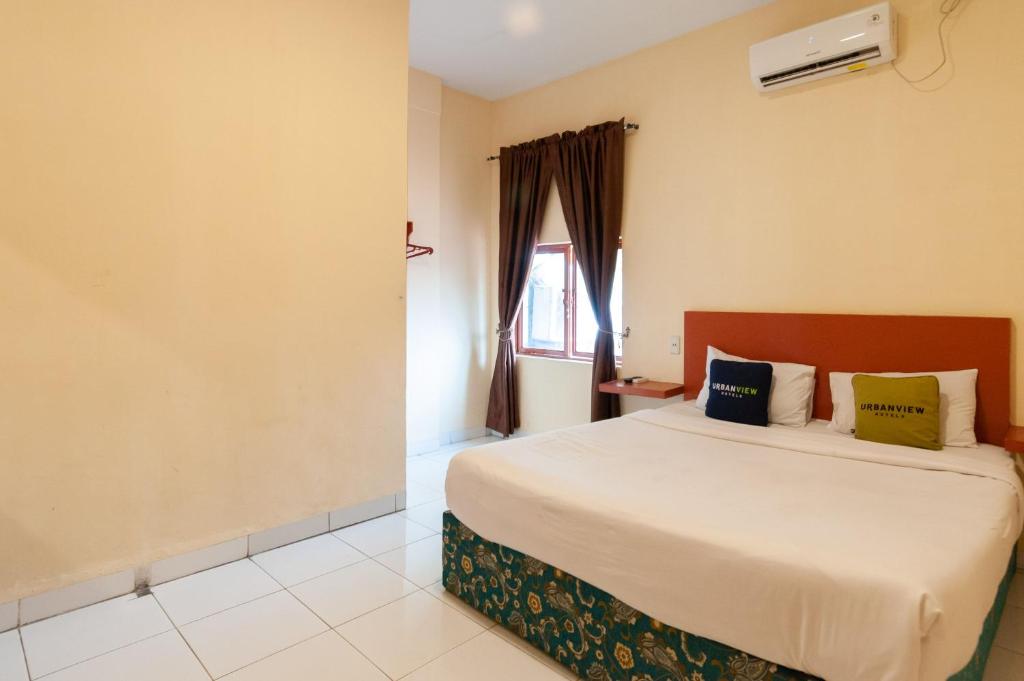 a bedroom with a bed and a window at Urbanview Hotel Syariah Residence Medan by RedDoorz in Medan