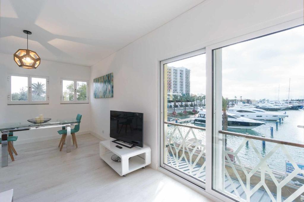 a living room with a tv and a large window at Boat View Marina Plaza By VilamouraSun in Vilamoura
