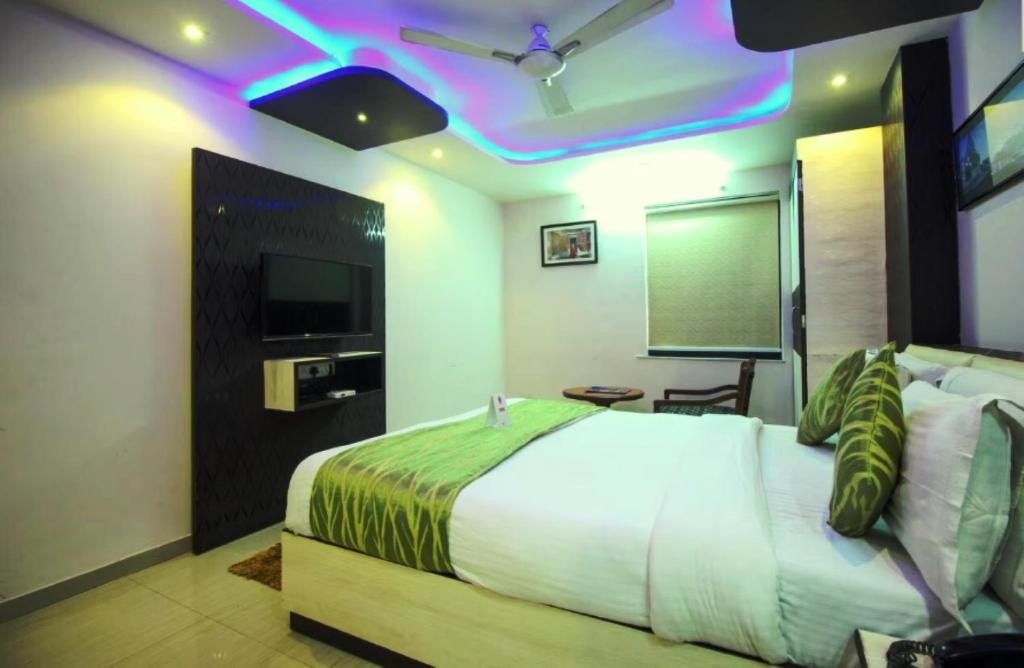 a bedroom with a bed with a green and white comforter at Hotel Sadbhav in Ahmedabad