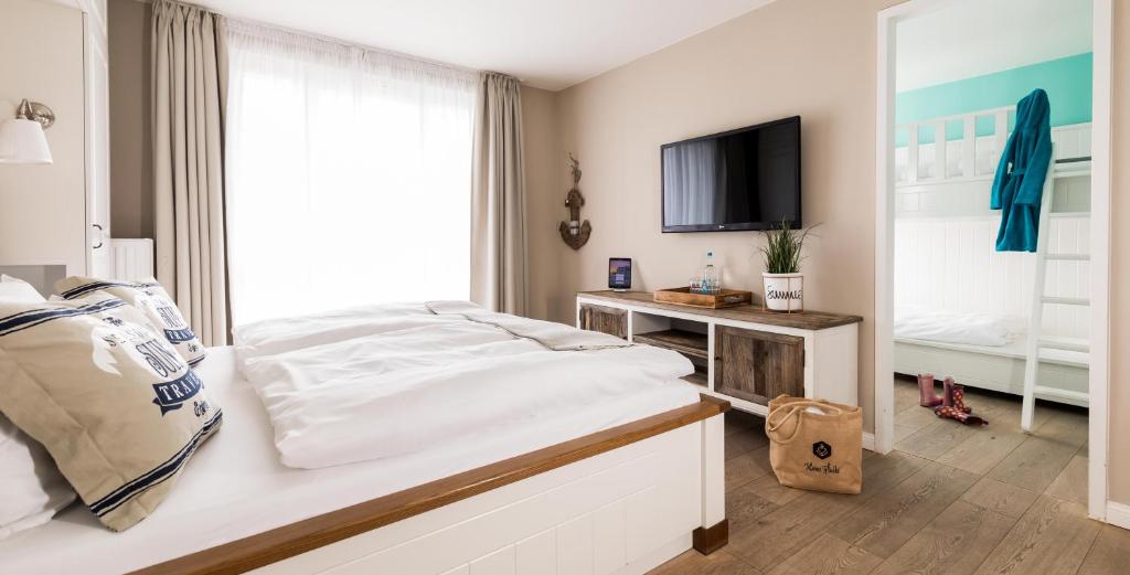 a bedroom with a white bed and a tv at Hotel Zweite Heimat in Sankt Peter-Ording