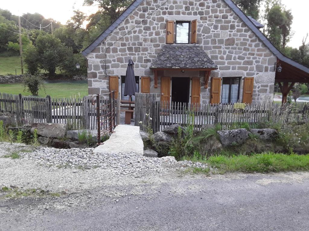 ein Steinhaus mit einem Holzzaun davor in der Unterkunft La maison d oscar in Menet