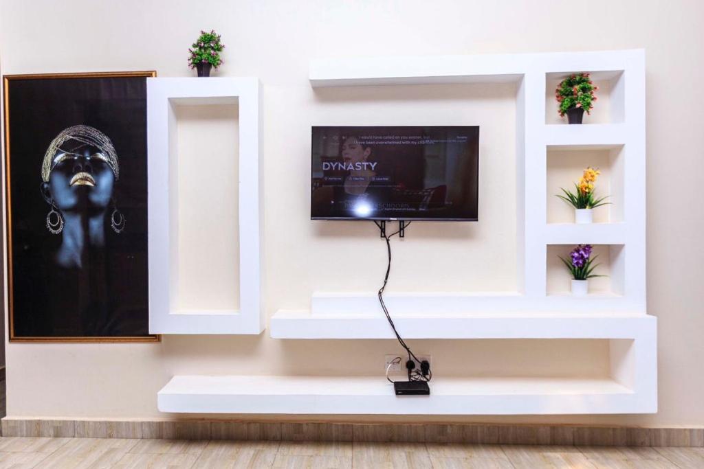 een televisie op een witte muur met een tv erop bij SkyGrey suites in Kampala