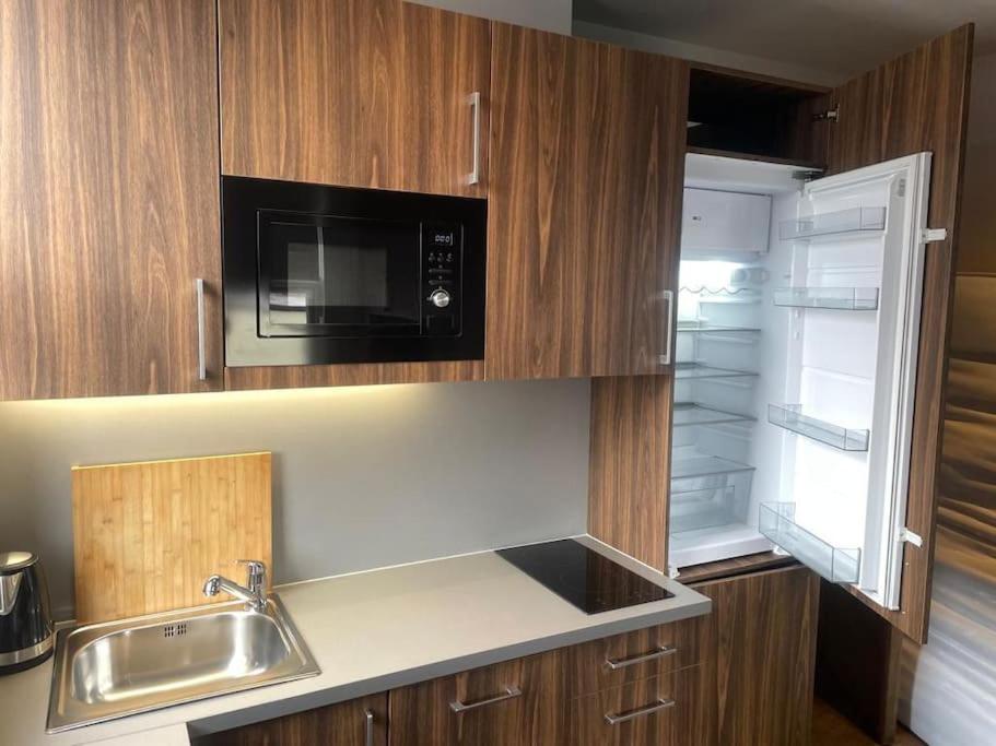 a kitchen with a microwave and a sink and a refrigerator at Cosy studio flat in Muswell Hill in London