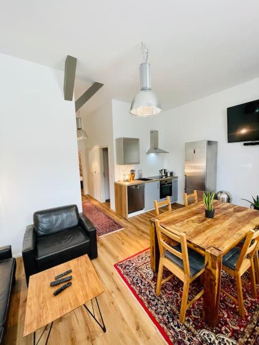 een woonkamer met een houten tafel en een keuken bij Charmantes Apartment in zentraler Lage in Braunschweig