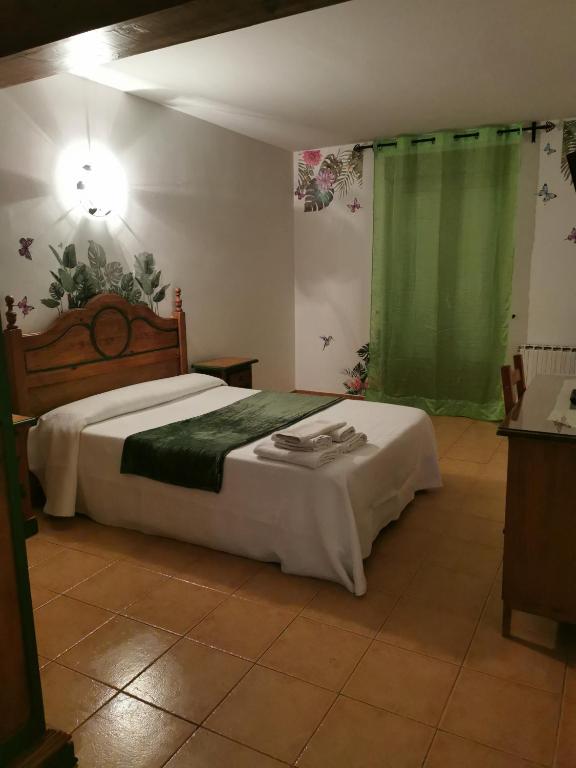 a bedroom with a bed and a green curtain at Posada La Maza in Arnuero