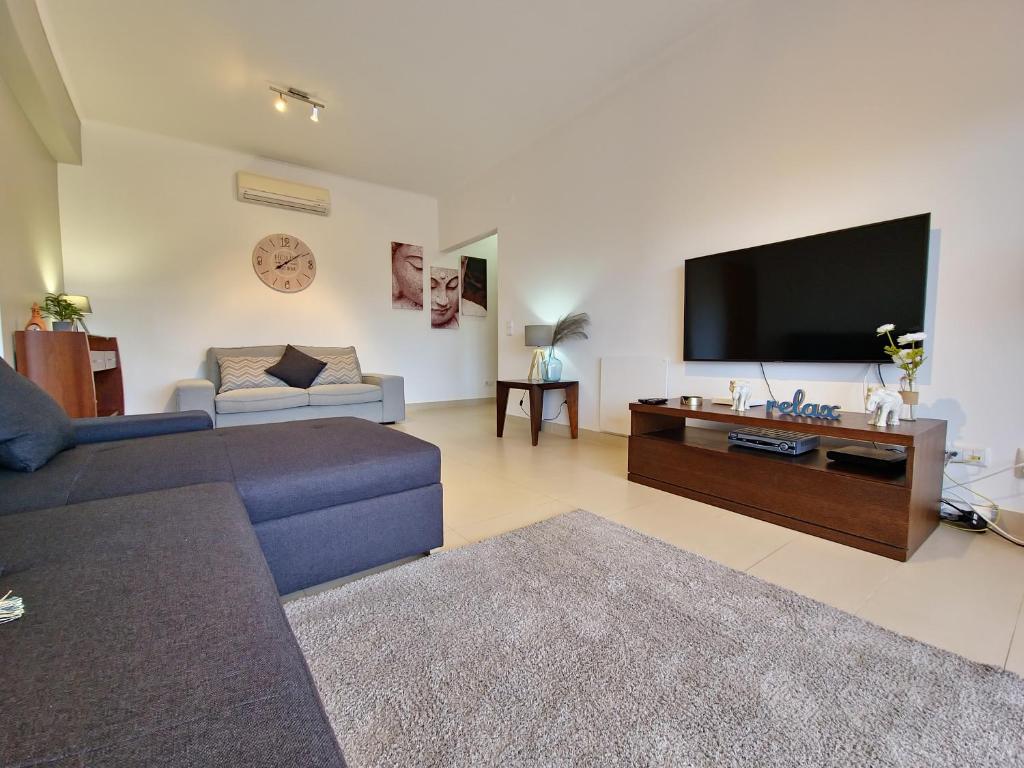 a living room with a couch and a flat screen tv at Apartamento Royal Garden T2 by YHA in Conceição