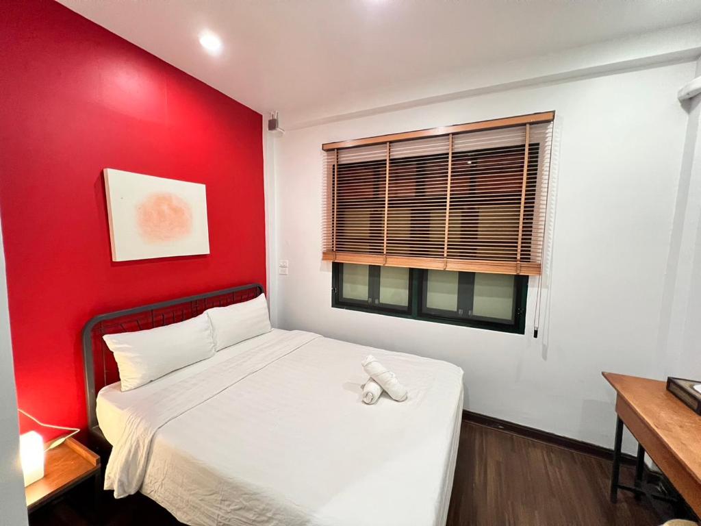 a bedroom with a red wall and a bed at Peace Factory Hostel in Bangkok