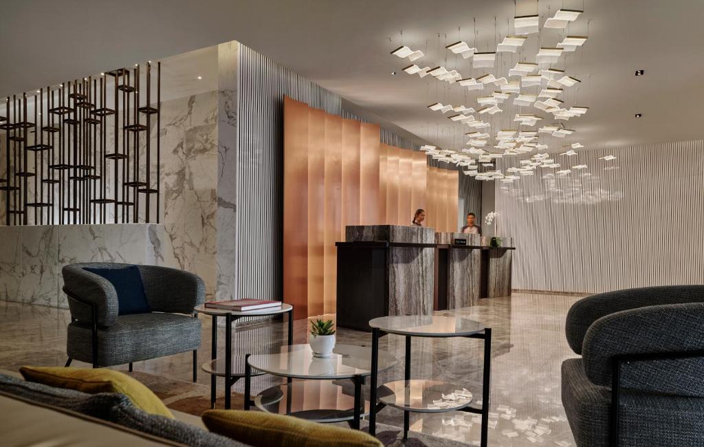 a lobby with chairs and tables and a chandelier at Pan Pacific Serviced Suites Kuala Lumpur in Kuala Lumpur