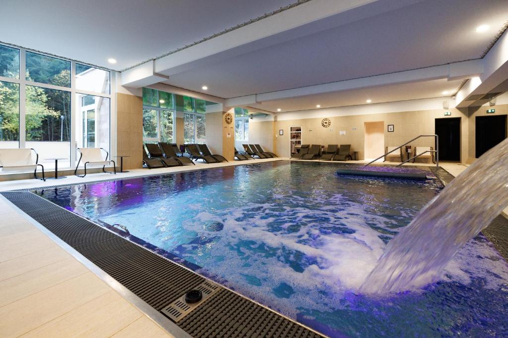 a swimming pool with a waterfall in a house at Hotel SPA Husseren Collections - Proche Colmar - Eguisheim in Eguisheim