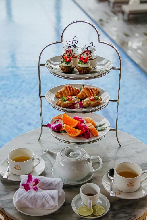 a table with plates of food and cups of coffee at Paris Deli Danang Beach Hotel in Danang