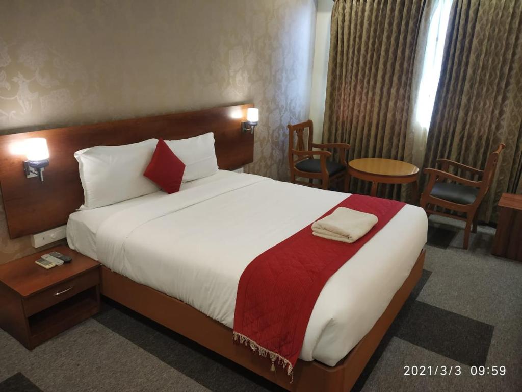 ein Hotelzimmer mit einem großen Bett und Stühlen in der Unterkunft DFRONT GOLDEN PALACE in Nāmakkal