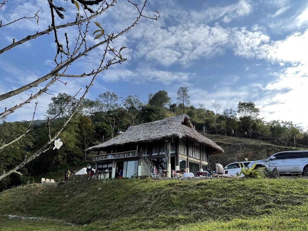 a house with a grass roof on a hill at Mường Ecolodge Hòa Bình in Hòa Bình